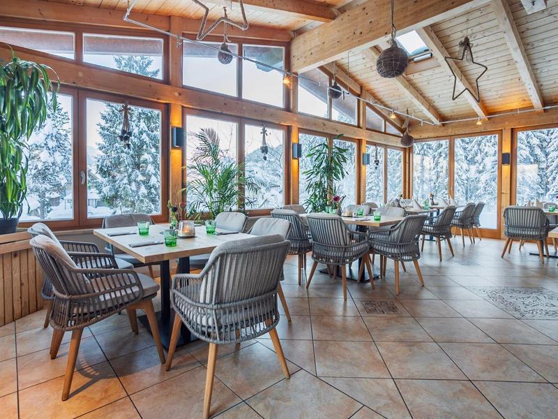Acogedor comedor de hotel con grandes ventanales y vista a árboles nevados.