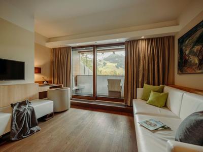 Gemütliches Wohnzimmer mit weißen Sofas, Holzboden, großem Fenster und braunen Vorhängen.