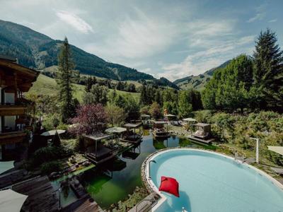 Runder Pool mit roten Kissen und grüner Natur in einem Bergresort.
