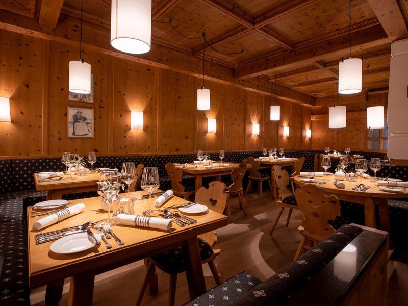 Gemütliches Restaurant mit Holzwänden, Decke, runden Tischen und warmem Licht.