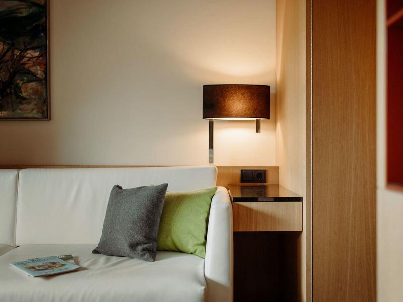 Weißes Sofa mit grauem und grünem Kissen, Beistelltisch und schwarzer Lampe in warmem Licht.