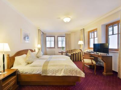 Jasny pokój hotelowy z podwójnym łóżkiem, biurkiem, telewizorem i wykładziną.