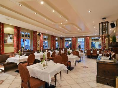 Elegancka restauracja z nakrytymi stołami, brązowymi krzesłami i dużymi oknami z czerwonymi zasłonami.