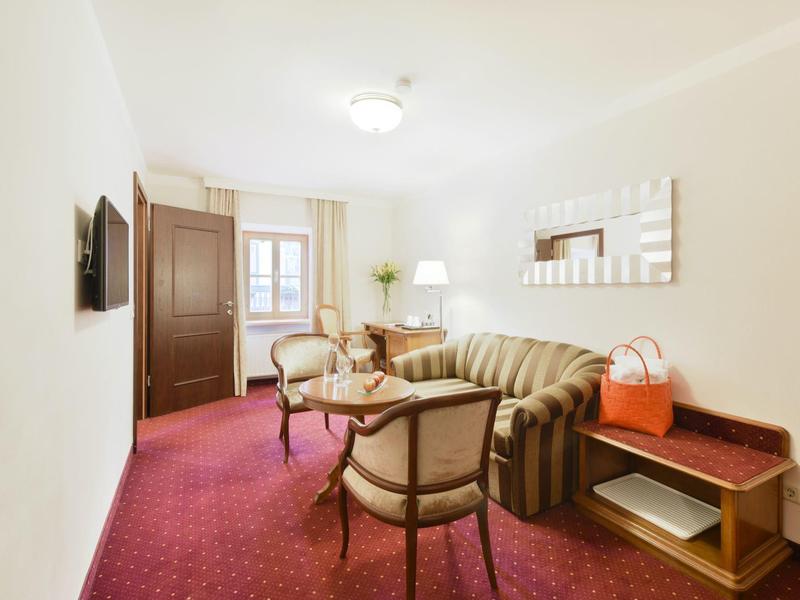 Camera d'hotel accogliente con poltrone, divano, tavolo e moquette rossa.