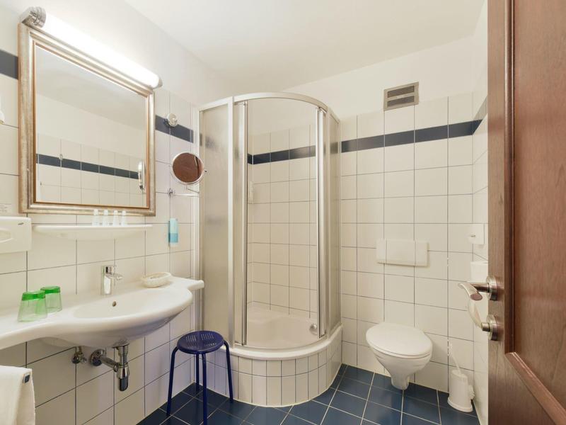 Bagno moderno con cabina doccia, lavandino, WC e pavimento piastrellato blu.