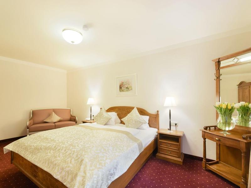 Camera d'hotel accogliente con letto matrimoniale, comodini, specchiera e illuminazione soffusa.