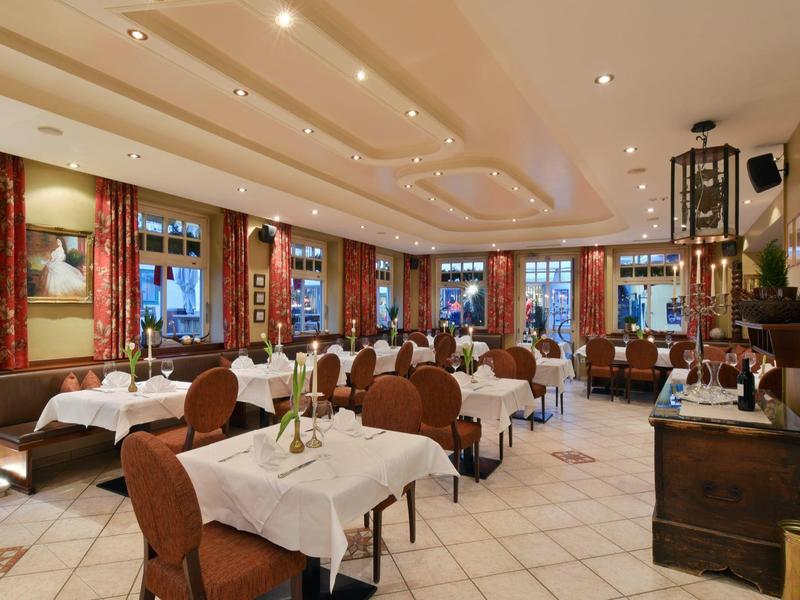 Sala da pranzo luminosamente illuminata con tavoli apparecchiati e sedie con tovaglie bianche.