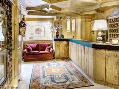 Coin salon d'hôtel confortable avec canapé, boiseries et tapis oriental.