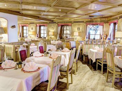 Salle à manger d'hôtel confortable avec sol en bois, nappes blanches et mobilier en bois.