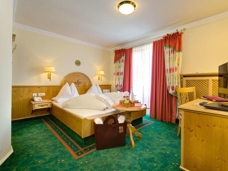 Gezellige hotelkamer met tweepersoonsbed, groen tapijt en houten meubels.