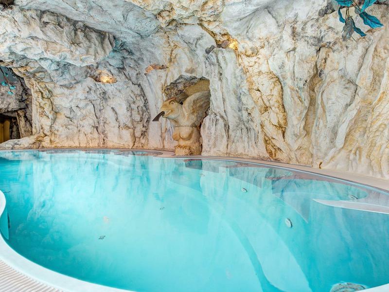 Verwarmd zwembad in een natuurlijke rotsgrot met helderblauw water.