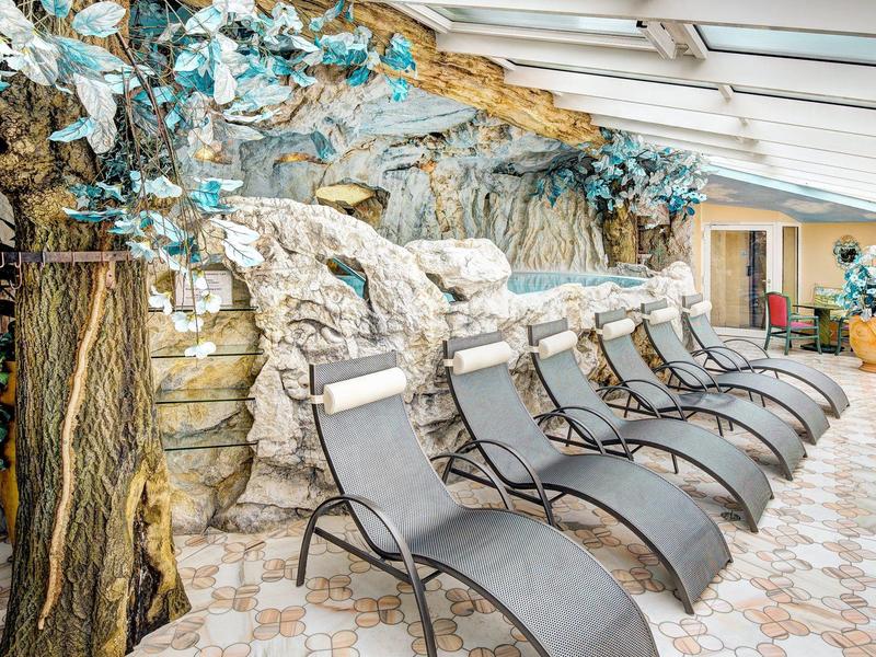 Ligstoelen in een lichte spa-ruimte met elegante stenen muur en decoratieve plant.