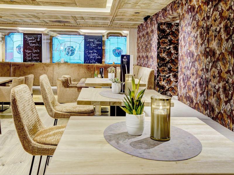 Moderne hotel eetgelegenheid met lichte tafels, comfortabele stoelen en decoratieve muren.