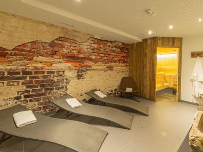 Odpočinková místnost s pohodlnými lehátky, saunou a rustikální cihlovou zdí v hotelu