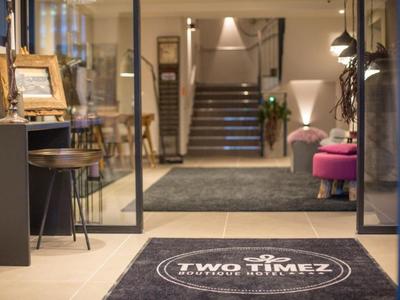 Entrance area of a modern hotel with carpet, seating, and stairs in the background