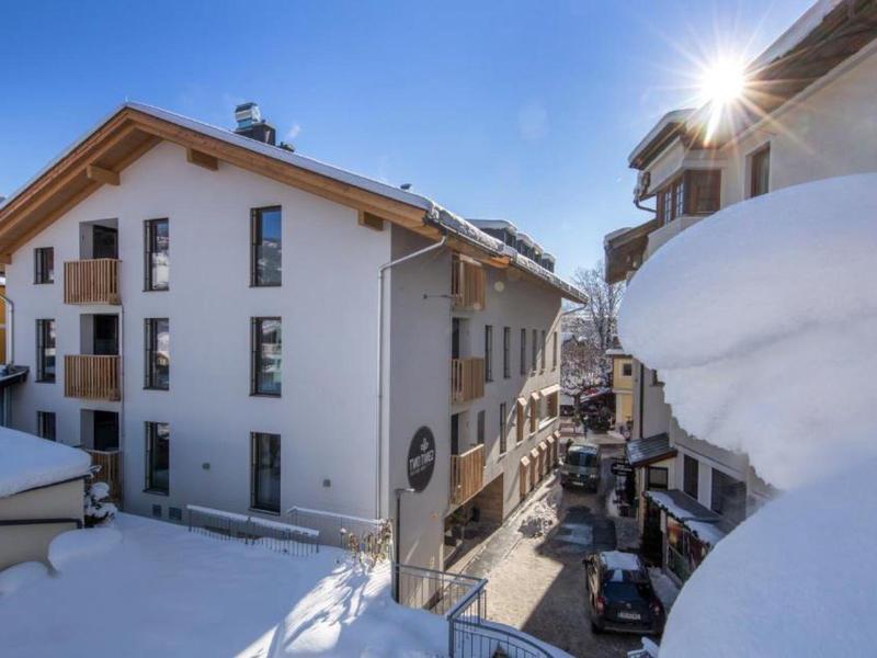 Zasněžené domy v horském městě s jasně modrou oblohou a sluncem.