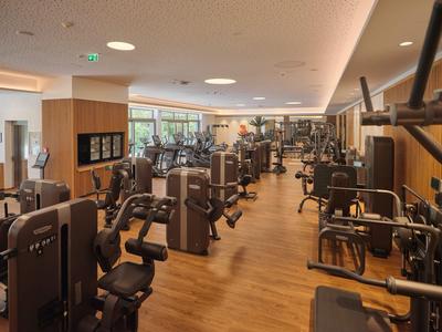 Moderne Fitnessstudio mit verschiedenen Trainingsgeräten und Holzfußboden.