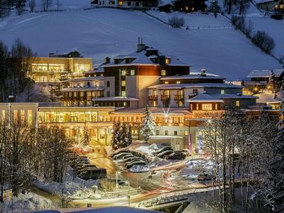Beleuchtetes Berghotel bei Nacht im verschneiten Winterland mit umliegenden Bäumen.