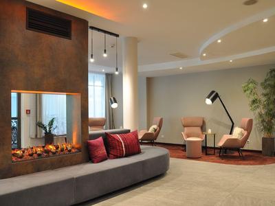 Modern eingerichteter Hotel-Loungebereich mit Kamin, Sesseln und gedämpfter Beleuchtung.