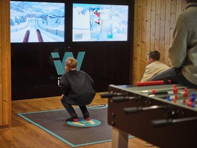 Persoon simuleert snowboarden op een indoorsimulator voor schermen.