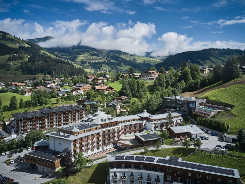 Uitzicht op een hotelresort in een groen, heuvelachtig dal onder een blauwe lucht.