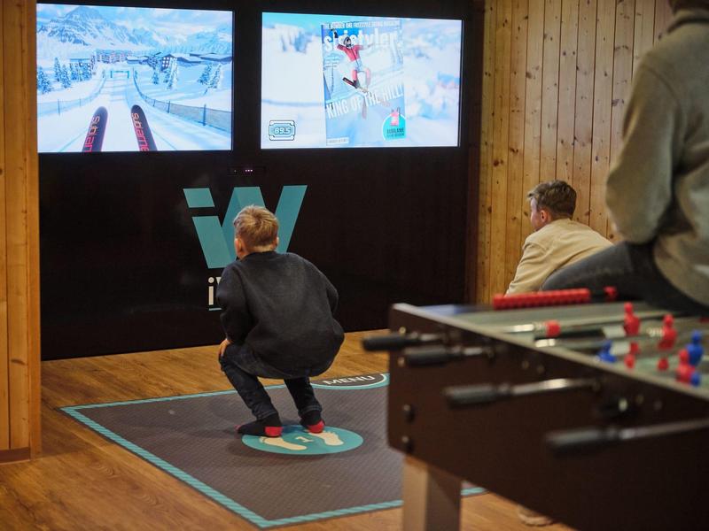 Persoon simuleert snowboarden op een indoorsimulator voor schermen.