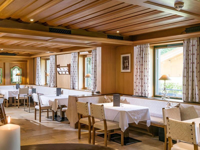Sala de comedor acogedora con muebles de madera, manteles blancos y grandes ventanas en un hotel.