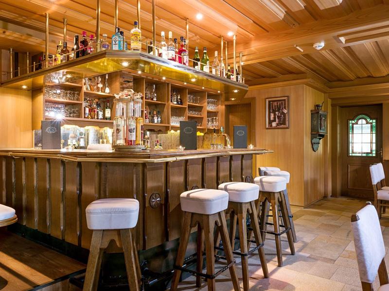 Elegante barra de hotel con revestimiento de madera, taburetes blancos y iluminación acogedora.