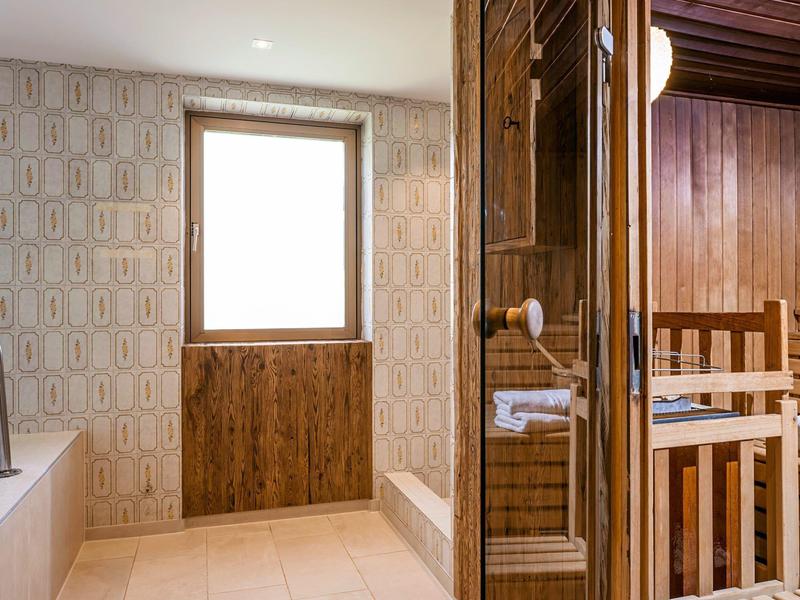 Baño luminoso con ventana, bañera y sauna con puerta y bancos de madera.