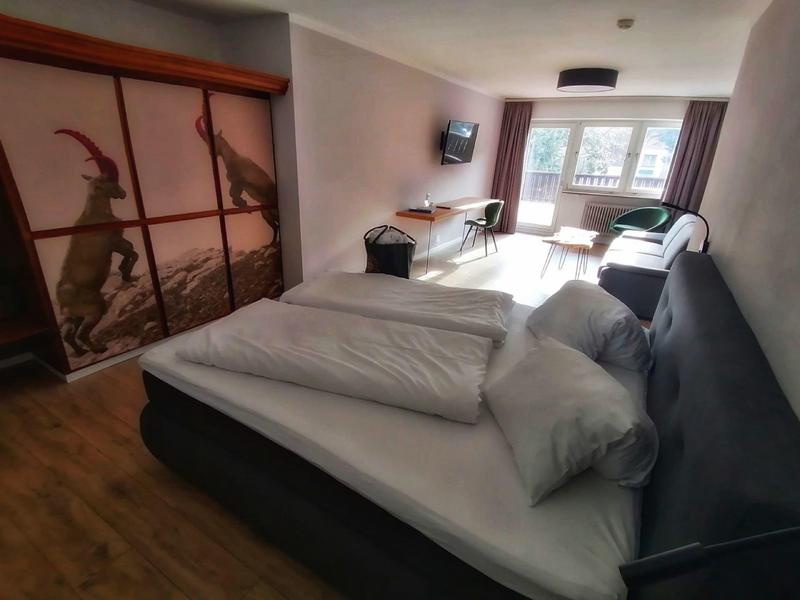 Habitación de hotel moderna con cama grande, escritorio, TV y ventana con cortinas.