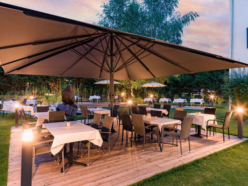 Terraza de restaurante al aire libre con mesas, sombrillas y luces al atardecer