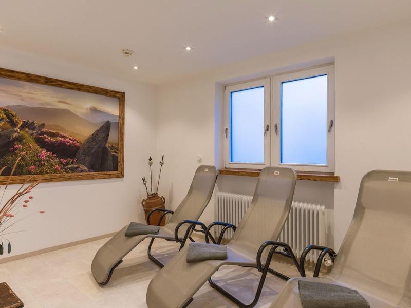 Zona de descanso con sillas reclinables beige, dos ventanas y un cuadro de paisaje en la pared.