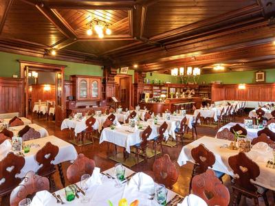 Ampia e accogliente sala da pranzo con mobili in legno finemente intagliati e tavoli apparecchiati.