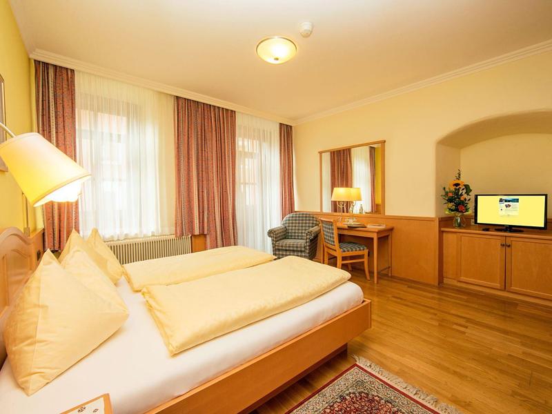 Chambre d'hôtel confortable avec lit double, bureau, télévision et éclairage chaleureux.