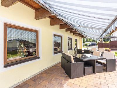 Pohodlná terasa s posezením a sluneční clonou připojená k domu.