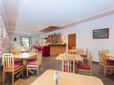 Brightly furnished dining room with wooden chairs and tables in a hotel restaurant.