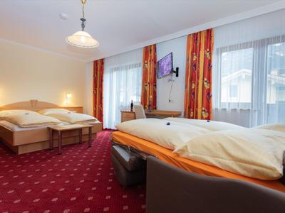 Cozy hotel room with two beds, red carpet, and large windows with curtains.