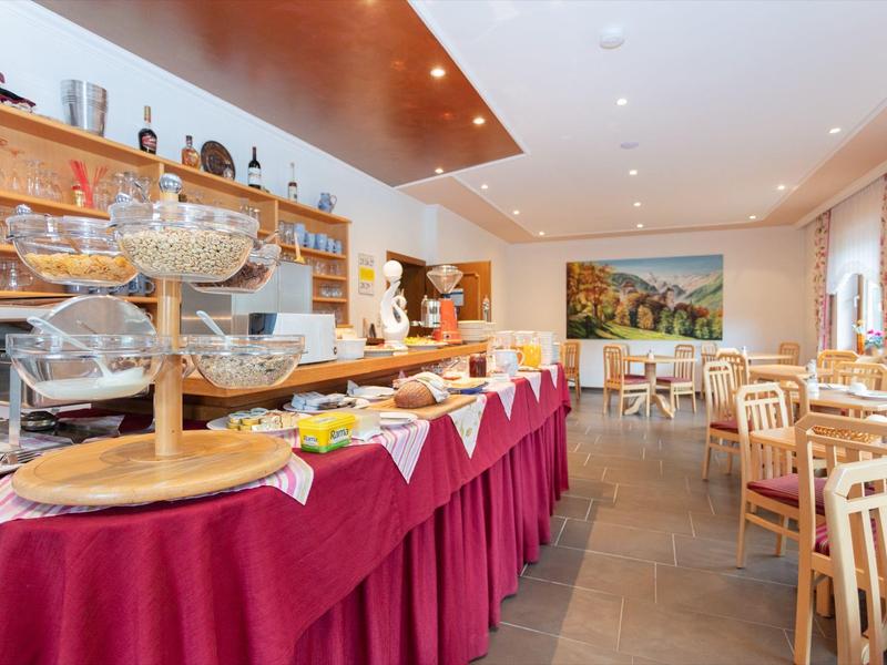 Světlá snídaňová místnost s bufetem a dřevěnými židlemi v hotelu.