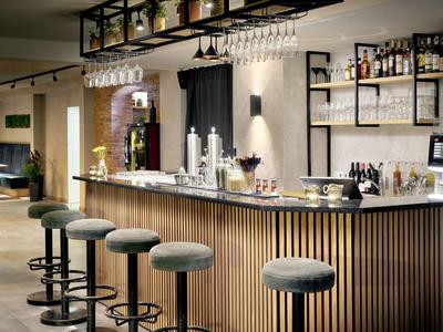 Area bar moderna dell'hotel con sgabelli in legno e bancone illuminato.