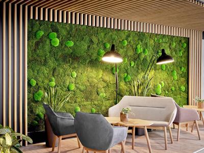 Area salotto moderna con sedie grigie e parete con muschio verde in un hotel