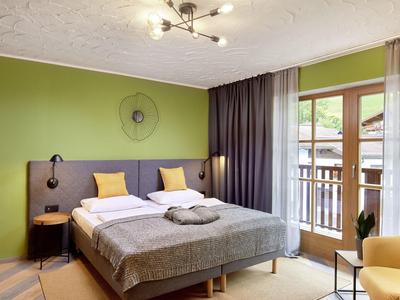 Nowoczesny pokój hotelowy z łóżkiem podwójnym, miejscem do siedzenia i balkonem z widokiem na zewnątrz.