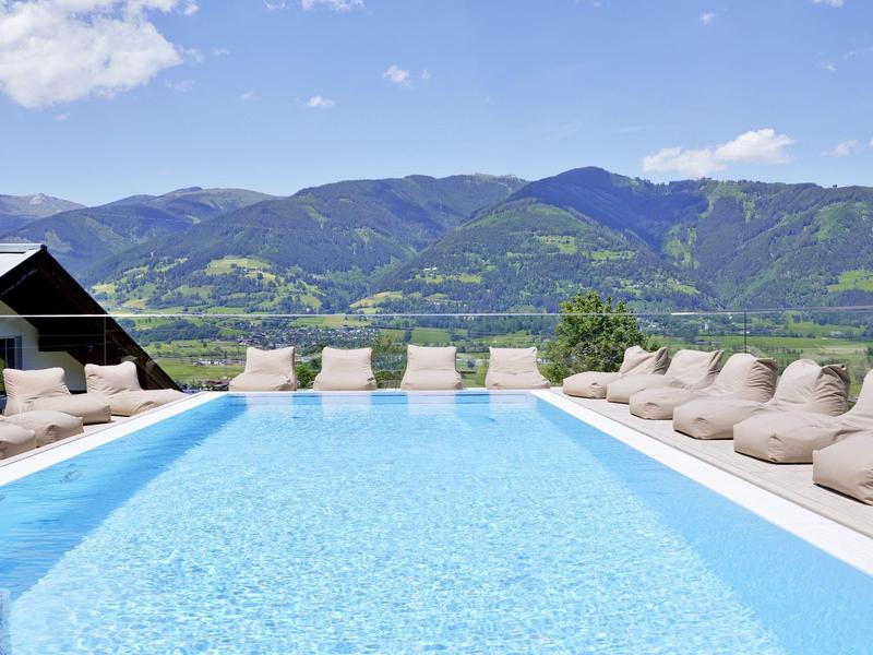 Zapraszający basen na zewnątrz z leżakami i wzgórzami w tle w słoneczny dzień.