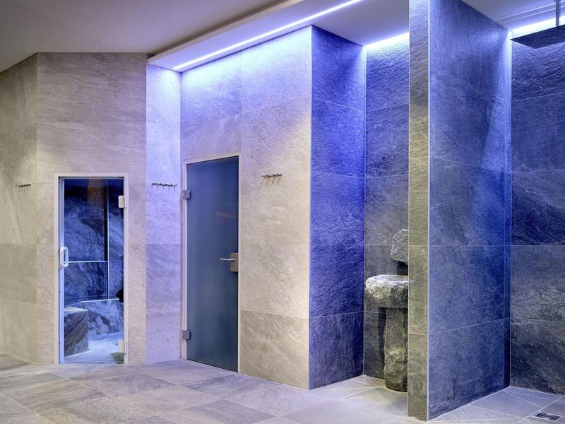 Nowoczesna łazienka hotelowa z podświetlanymi kabinami prysznicowymi i szarymi płytkami