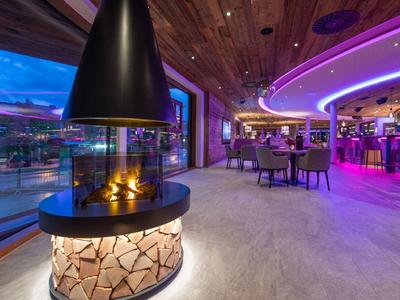 Modern hotel interior with fireplace, large window wall, and lounge area with colorful lighting