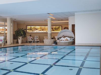 Vnitřní bazén s čistou vodou, lehátky a dekoracemi v relaxační zóně.