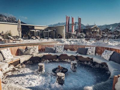 Pohodlná venkovní vířivka s posezením obklopená sněhem a horami.