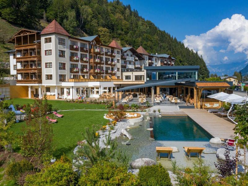 Hotel s bazénem a lehátky v horské krajině pod modrou oblohou.