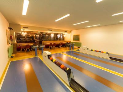 Salle de bowling intérieure avec plusieurs pistes et coin salon en arrière-plan.