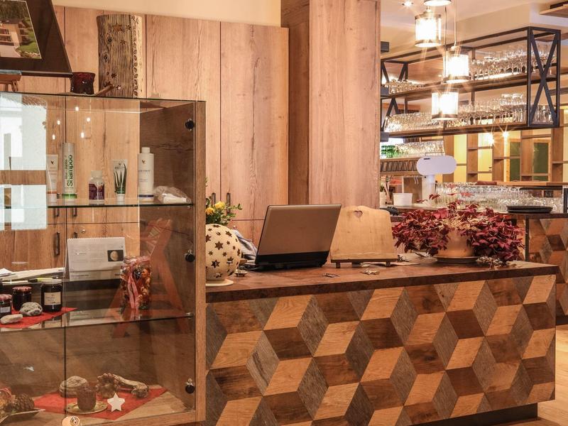 Reception with modern geometric wood pattern and glass display case in warmly lit hotel area.