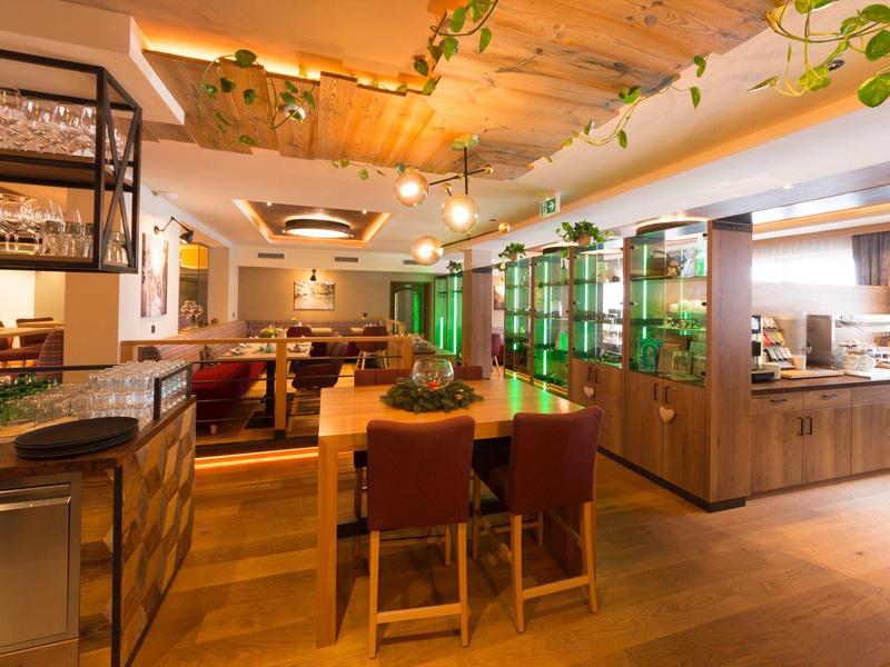 Cozy hotel restaurant area with wooden furniture, green accents, and warm lighting.